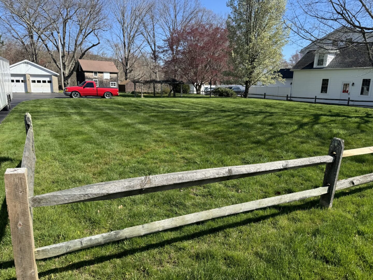 A red truck parked in the grass behind a fence.